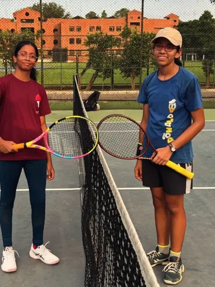 Two of our players posing at the net after a competitive match. We encourage healthy competition and sportsmanship among all our students.