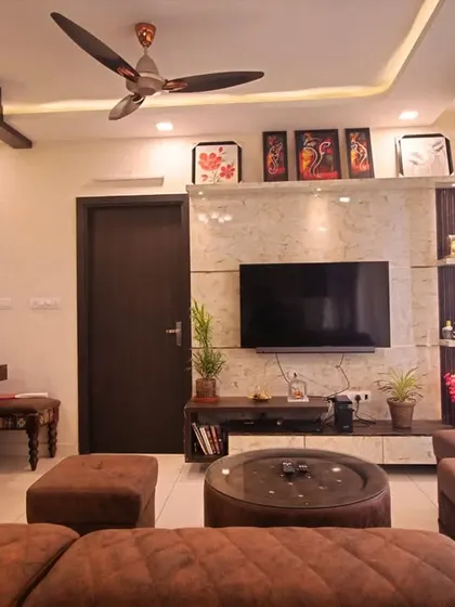 This living room design combines rich wood tones with a comfortable, modern sofa and a unique false ceiling detail, creating a warm and inviting atmosphere.