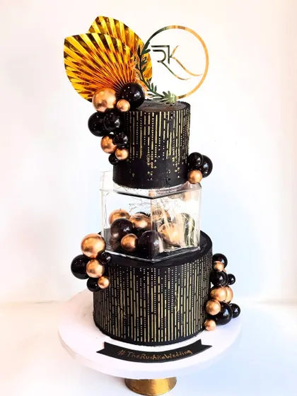 A different view of the black and gold wedding cake, showing the custom initial topper. This modern design is for couples who want to make a bold statement.