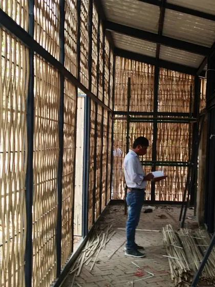 An architect on-site at the Artist Residency, inspecting the woven bamboo screens. This image captures the hands-on process of realizing our vision for a structure that is deeply connected to its materials and natural setting.