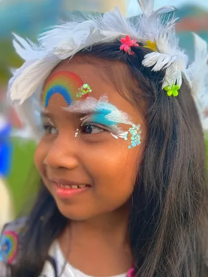 A beautiful shot of a girl with a rainbow and cloud design, complete with a feather hairpiece for a full festival look.