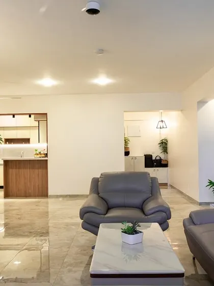 An open-concept living space that connects the seating area with the kitchen in the background. The consistent color palette and flooring create a cohesive and expansive feel.