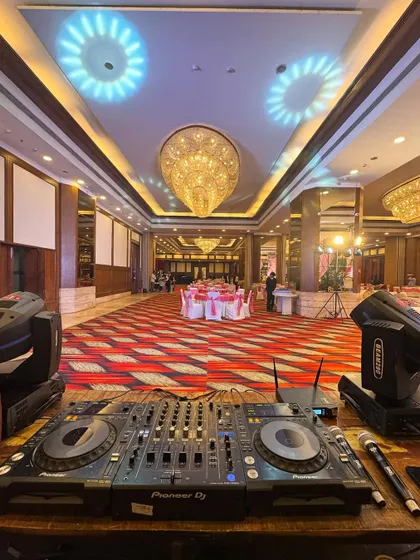 My point of view before a Punjabi wedding reception. The professional Pioneer DJ console is set up with a clear view of the grand ballroom, ready to get the party started with spot lighting and ambient effects.