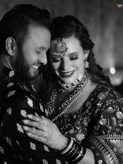 An intimate black and white close-up of a couple embracing, both with joyful smiles. This candid shot captures a genuine moment of happiness and connection between them.