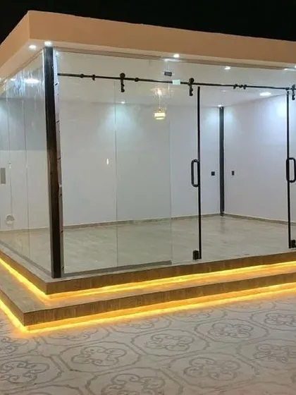 A unique glass cabin design featuring exterior sliding glass doors on a barn-style track system. This structure is elevated on a platform with integrated step lighting, showcasing our ability to incorporate custom features and modern aesthetics into our prefab rooms.
