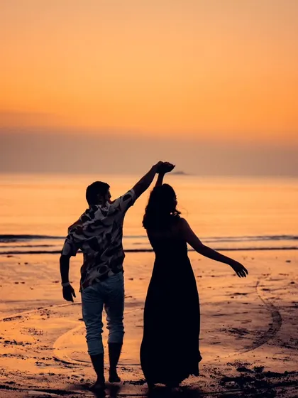 A beautiful silhouette of a couple dancing on a Mumbai beach at sunset. The vibrant sky and romantic pose make this a classic and stunning pre-wedding photograph.