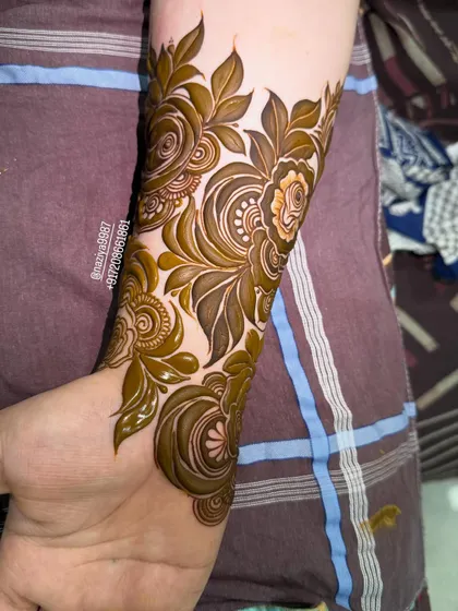 A close-up of a floral arm band with swirling rose patterns. The detail in the leaves and petals is what makes it special.