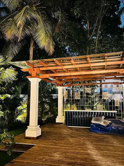 A beautifully lit pergola and deck area in a large garden. This demonstrates our skill in creating functional outdoor 'rooms' that can be enjoyed day and night, surrounded by lush tropical planting.
