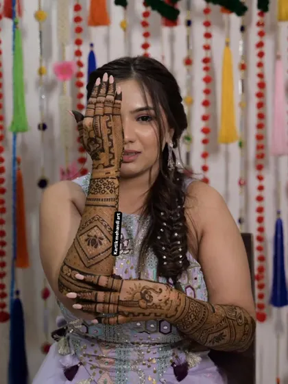 A bride showing off her back-hand mehandi. The design features a large lotus motif and intricate patterns, creating a bold and modern look.