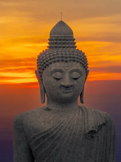 A close-up shot of the Big Buddha statue in Phuket against a fiery sunset, celebrating the peace and wisdom of Gautam Buddha on Buddha Poornima.