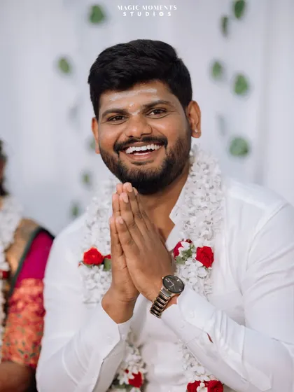 A portrait of the happy groom during his engagement ceremony, greeting guests with a traditional namaste.