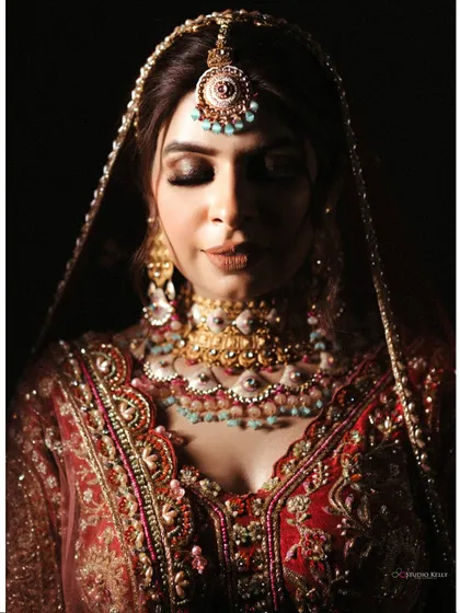 A stunning, dramatic close-up portrait of the bride, her face beautifully lit against a dark background.