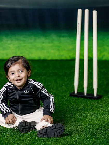 Even the littlest ones can join the cricket fun. This baby is all smiles, sitting on the "pitch" in his sporty Adidas tracksuit.