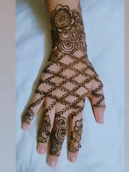 This design shows how beautifully a leafy jaal pattern can cover the back of the hand. The delicate net is framed by a bold floral cuff and intricate designs on the fingers.