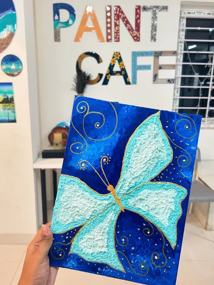 A beautiful butterfly texture art painting on a deep blue background, held up for display.