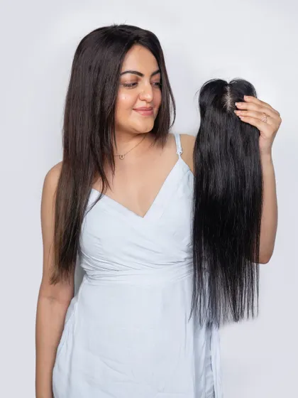 A model holding our silk topper. This piece is designed to blend seamlessly, providing a solution for thinning hair that looks and feels completely natural.