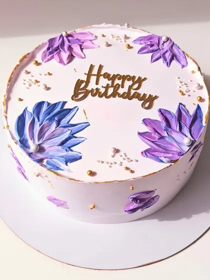 An aesthetic birthday cake with abstract, palette-knife painted flowers in shades of purple and blue. The gold accents add a touch of modern elegance.