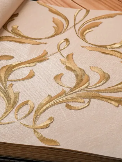 This wallpaper features an elegant gold leaf scroll pattern on a neutral, textured background. It's a classic design that adds a touch of glamour and sophistication without being overwhelming.