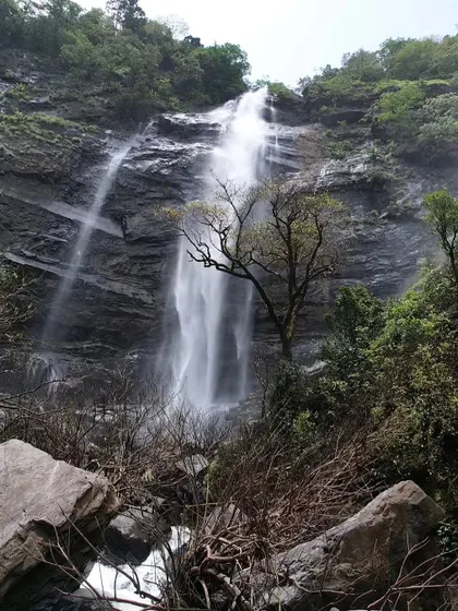 A stunning view of a waterfall cascading down a rocky cliff face. The geology of the Western Ghats is as fascinating as its biology.