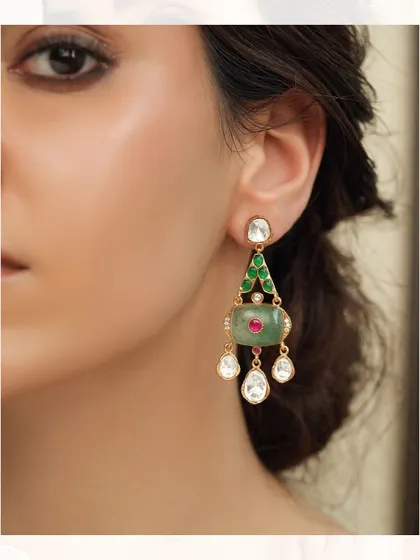 Delicate and artistic, these earrings feature a triangular design with green stones and dangling polki diamonds.