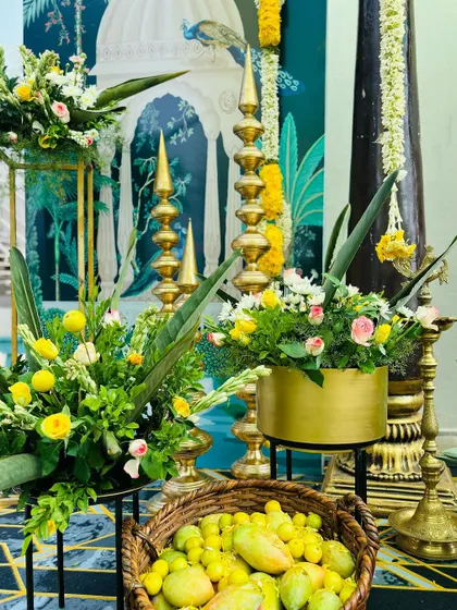 Details of the Haldi decor, including a basket of mangoes, brass lamps, and floral arrangements, all contributing to a rich, traditional atmosphere.