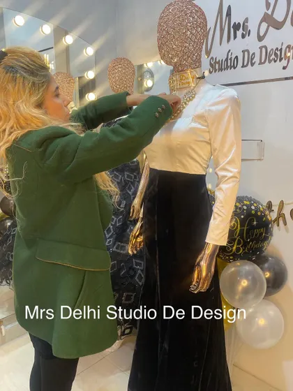 Adjusting the final details on our Bollywood-inspired gown. The contrast between the crisp white top and the rich black velvet skirt creates a look of pure elegance.