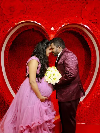 A loving couple's maternity portrait. They pose forehead to forehead inside the heart-shaped prop, creating a romantic and intimate photo.