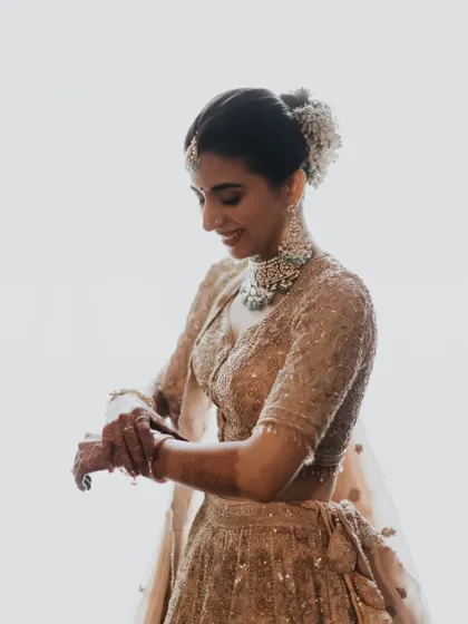 A beautiful silhouette shot. The soft light highlights her profile and the delicate details of her bun and lehenga.