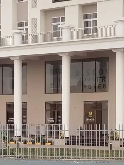 A detailed shot of the main entrance colonnade at EuroSchool, showcasing the large glass panels that create a transparent and welcoming lobby space.