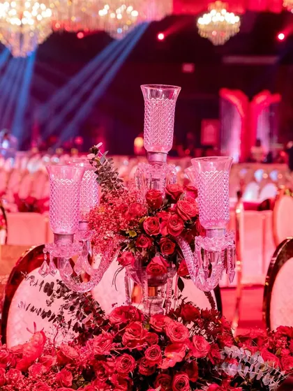 A duplicate of image 38, this photo provides a detailed look at a guest table centerpiece, where a crystal candelabra rises from a bed of lush red roses.