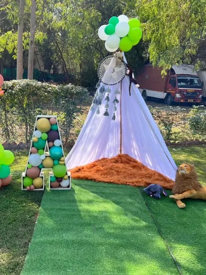 A cozy teepee tent and a large balloon-filled letter 'A' as part of the outdoor jungle theme decor.