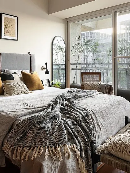 The 'Reweave Stories' bedroom is a cozy, layered space. A custom-strapped headboard, soft linens, and warm lighting create an inviting atmosphere perfect for rest and relaxation.