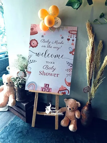 The welcome setup for the rustic baby shower, featuring a personalized sign on an easel, flanked by cute teddy bears and a vase of pampas grass to introduce the theme.