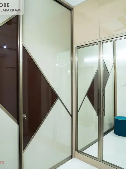 A walk-in wardrobe from the Sithalapakkam project, showcasing custom Aristo sliding doors with a geometric pattern and integrated lighting.