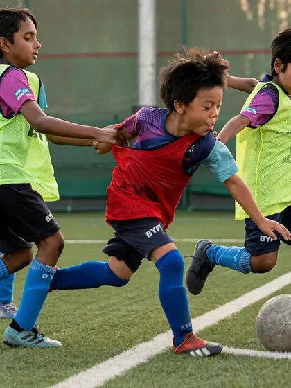 Intense action during a training match, with one player trying to get past two defenders.