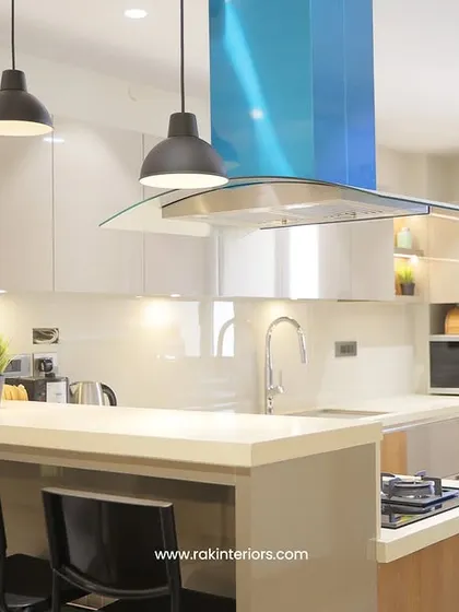 A kitchen designed for space optimization, with a compact breakfast bar, sleek white cabinets, and a modern glass chimney hood.