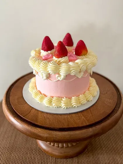 A sweet and simple vintage-style cake. This pink buttercream cake is decorated with classic piping, topped with fresh strawberries for a fresh and pretty look.