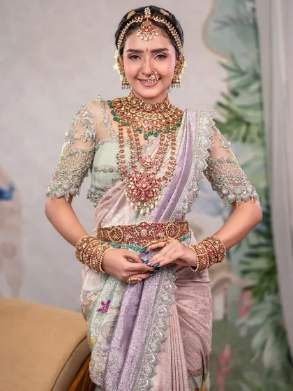 This portrait is all about timeless beauty with a modern twist. The pastel-colored saree and intricate jewelry are set against a beautiful hand-painted backdrop, creating a look that is both traditional and refreshingly contemporary.