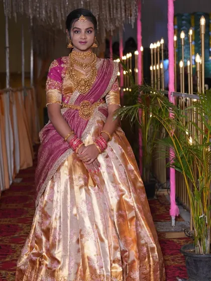A full-length view of the client at her half-saree ceremony, showcasing the beautiful brocade skirt and matching embroidered blouse.