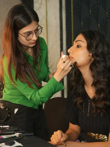 A student artist applies the final touches to a model's lips backstage at Bombay Times Fashion Week. Precision and focus are key in this fast-paced environment.