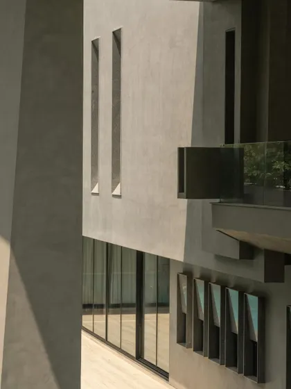 Close-up details of the concrete facade, showing the interplay of sharp angles, deep recesses, and smooth surfaces. These shots emphasize the building's sculptural and tactile qualities.