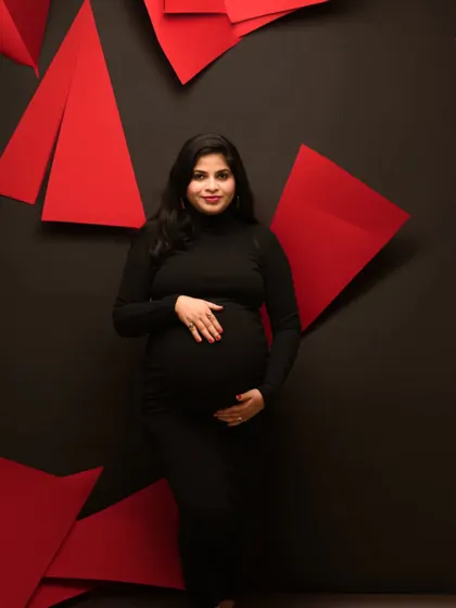 A bold and modern studio portrait. The black dress against a black background with red geometric shapes creates a striking and artistic composition.