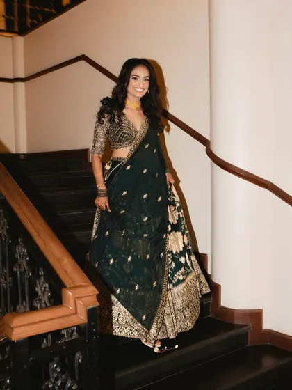 A glowing and gorgeous bride ready for her reception. The dark, embellished lehenga is balanced with a luminous makeup look and soft, wavy hair.