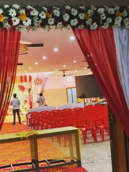 A simple yet effective entrance decoration for a hall, using red and white drapes and a floral border.