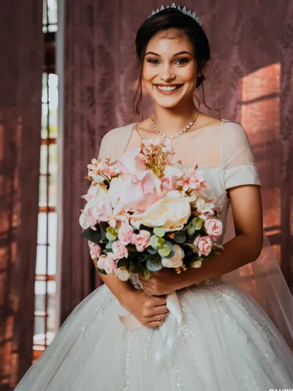 A radiant bridal portrait, capturing the bride's bright smile and the beautiful details of her gown and bouquet.