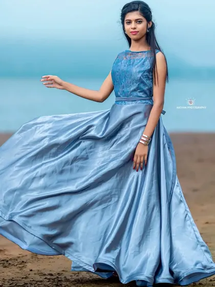 The flowing skirt of the silvery-blue gown creates beautiful movement, ideal for beach or waterside maternity photos.