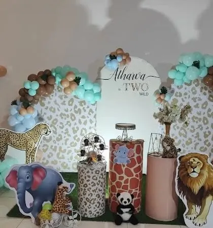 A "Two Wild" birthday theme with a cheetah-print backdrop and cutouts of various safari animals like a cheetah, lion, and elephant.