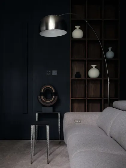 The family room is a cozy, intimate space designed for movie nights. The dark walls, deep shelving, and comfortable grey sofa create a perfect environment for relaxation.