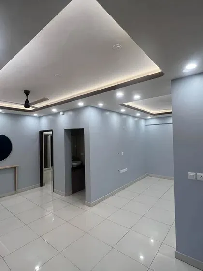 An empty living hall with a completed false ceiling and lighting. The clean, expansive space is ready for furniture and decor.
