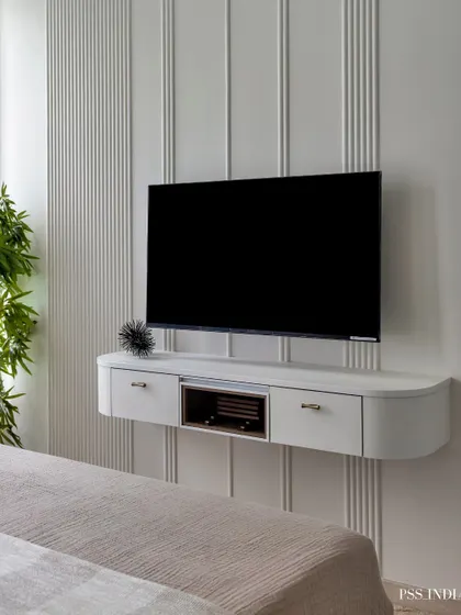 A sleek, floating TV unit elevates this bedroom's style. Its crisp white finish and the vertical paneling on the wall create a modern and clean aesthetic, proving that media storage can be elegant.